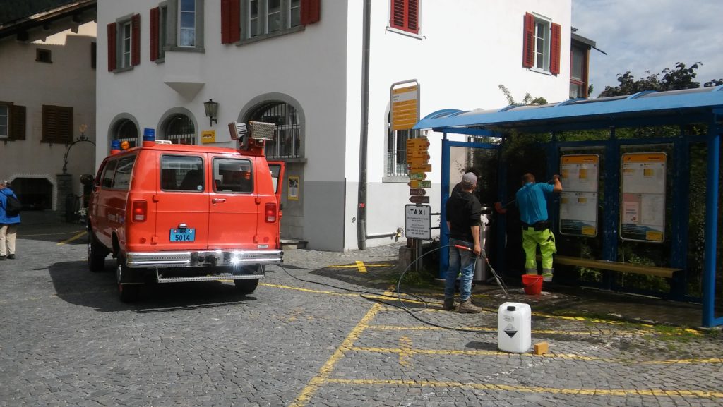 Mit dem Wasser vom Feuerwehrauto wird die Bushaltestelle gereinigt.
